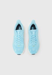 Αθλητικά παπούτσια σε ανοιχτό γαλάζιο με επάνω μέρος από διχτυωτό υλικό, στρογγυλή μύτη, κορδόνια σε τονική απόχρωση και λευκή μεσαία σόλα. Κίτρινη διακριτική λεπτομέρεια κοντά στη μύτη και υφασμένες λεπτομέρειες.