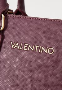 Borsa Valentino in materiale borgogna testurizzato con dettaglio del logo dorato. Presenta una finitura liscia e una forma strutturata.