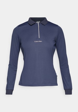 Polo à manches longues navy en tissu lisse, doté d'un col côtelé, d'une fermeture éclair blanche et d'un logo "Calvin Klein" brodé sur la poitrine.