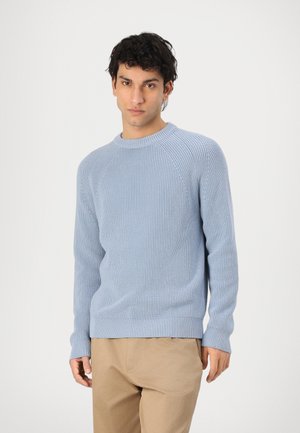 Light blue ribbed knit sweater, crew neckline, long sleeves, and fitted cuffs. Paired with beige trousers, featuring a straight cut.