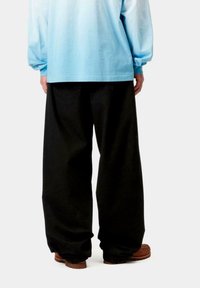Pantalones anchos negros hechos de una tela pesada, con una textura suave y un ajuste relajado, combinados con una camisa de manga larga azul claro.