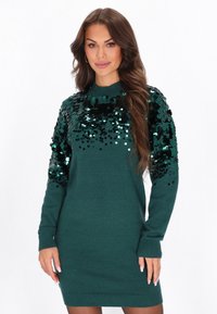 Abito maglione verde con collo alto, caratterizzato da dettagli in paillettes sulle spalle. Tessuto a maglia, maniche lunghe e silhouette aderente.