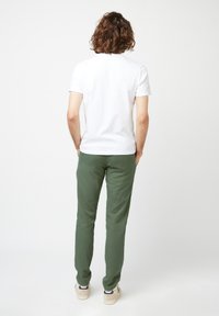 Witte korte mouwen t-shirt gecombineerd met groene sweatpants, met een relaxte pasvorm, zachte stof en contrasterende sneakers.
