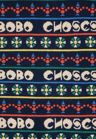 Un textil con un fondo azul marino y patrones coloridos, que incluyen formas geométricas, motivos florales y texto en letras estilizadas.