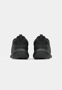 Mustat urheilukengät, joissa on teksturoitu päällinen, pehmustettu kanta ja kuvioitu kumipohja, nähtynä takaa. Kevyt muotoilu.