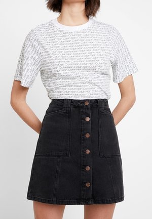 Biała koszulka z krótkim rękawem z nadrukiem logo Calvin Klein; czarna spódnica dżinsowa o kroju A z przodu zapinana na guziki i z dwoma kieszeniami.