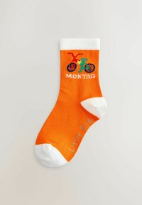 Calza di cotone arancione con grafica di una bicicletta e la parola "MONTAG" in bianco. Accenti bianchi alla parte superiore e sulla punta. Nome del marchio "Little Bird" stampato.