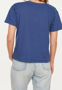 Sininen puuvillapaita, jossa on pyöreä kaula-aukko ja lyhyet hihat, rento malli ja suora helma. Yhdistetty vaaleansinihin farkkuihin.