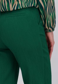 Groene textuur broek met een aansluitende silhouet, voorzien van een achterzak en gecombineerd met een gestreept, langarmtop in contrasterende kleuren.