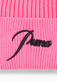 Roze gebreide beanie met een gestructureerd ribbelontwerp. Zwarte geborduurde "Puma"-logo prominent weergegeven aan de voorkant.