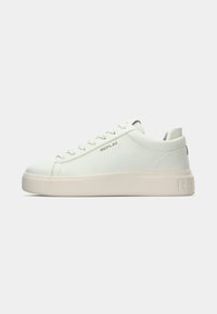 Zapatilla blanca de cuero con un acabado suave, suela plana y logo "REPLAY" en relieve en el lateral. Cuenta con seis ojales y una punta redondeada.