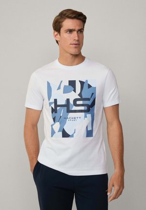T-shirt bianca in cotone con un motivo grafico astratto blu e testo "HACKETT SPORT" in nero al centro. Maniche corte e collo tondo.