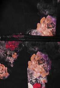 Tissu noir avec un motif floral comprenant de grandes fleurs pêche et violettes ainsi que de plus petites fleurs rouges et blanches.