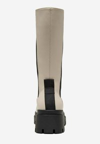 Stivale beige fino al ginocchio con pannelli laterali elastici neri, tessuto testurizzato e suola nera spessa. Presenta una linguetta centrale sul retro.