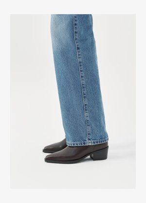 Bruine leren enkellaarzen met een spitse neus en blokhak, gecombineerd met lichtblauwe recht gesneden jeans, die een schoon en eenvoudig ontwerp tonen.
