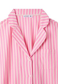 Camicia da pigiama a righe rosa con righe verticali di rosa chiaro e scuro, colletto a scialle, taschino frontale e chiusura a bottoni. Etichetta del marchio visibile all'interno.