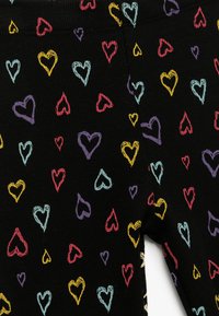 Svart tyg med ribbad textur som har färgglada hjärt-mönster i rosa, rött, lila, gult och blått, slumpmässigt fördelade över ytan.