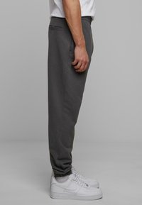 Grå sweatpants med elastiske manchetter, sidelommer og en glat tekstur. Kombineret med hvide sneakers med perforeret design.