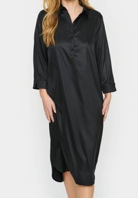 Svart satin klänning med krage, knappslå och trekvartslånga ärmar. Slät textur med en något lös passform och sidov slit.