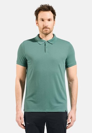 Short-sleeve polo shirt in solid teal, featuring a collared neck, button placket, and a smooth texture. Dark label on the lower left side.
