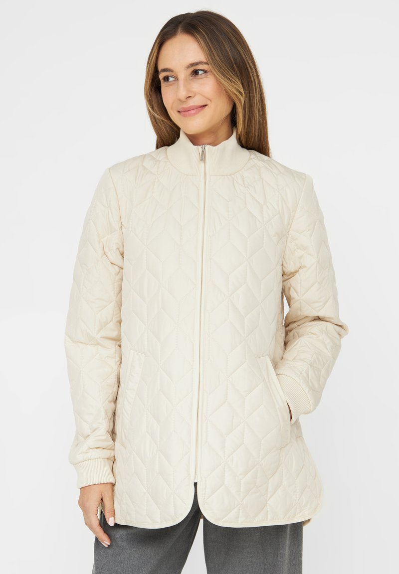 Quilted cream jacket with a stand-up collar, front zipper, and two pockets. Features ribbed cuffs and curved hem. Smooth texture.