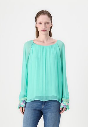 Lett, gjennomsiktig mintgrønn bluse med rund hals, lange ermer og broderte blomstermotiver på mansjettene.