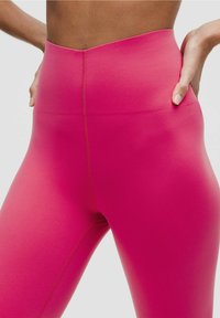 Legginsy z wysokim stanem w intensywnym różowym kolorze, wykonane z gładkiego, elastycznego materiału i minimalnymi szwami, co zapewnia smukły, dopasowany wygląd.