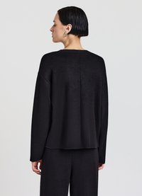 Maglione nero lavorato a maglia con vestibilità comoda, maniche ampie e scollo a coste. Presenta una texture liscia e un dettaglio con cucitura posteriore.