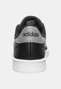 Czarny skórzany sneaker z szarymi akcentami i białą podeszwą. Charakteryzuje się zaokrąglonym noskiem oraz haftowanym logo na pięcie. Gładka faktura.