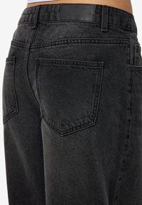 Zwarte denim jeans met een gestructureerde afwerking, twee achterzakken en een leren label op de tailleband. Standaard vijfzakendesign.