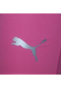 Rosa Stoff mit glatter Textur zeigt ein silbernes Puma-Logo, das eine springende Katze darstellt, vor einem einfarbigen Hintergrund.