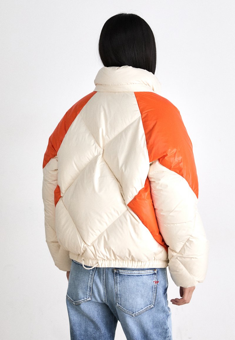 Giacca imbottita con un design a blocchi di colore beige e arancione, colletto alto e orlo elasticizzato, con una superficie liscia e lucida.