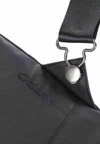 Bolso ligero negro para el hombro con tela texturizada, herrajes metálicos y logo en relieve. Cuenta con una correa resistente con hebilla ajustable.