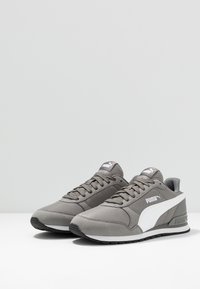 Graue Sneakers mit einem Obermaterial aus Mesh und Wildleder, weißen Akzenten, runder Zehenpartie und flacher Gummisohle; ausgestattet mit einer Schnürung und gepolstertem Schaft.