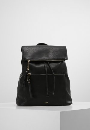 Schwarzer Lederrucksack mit Vorderreißverschlusstasche, Kordelzugverschluss und Klappe, auf weißer Oberfläche vor einfarbigem Hintergrund platziert.