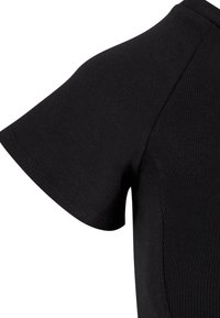 Gros plan d'un T-shirt noir à manches courtes avec une texture côtelée et des coutures apparentes sur le vêtement.