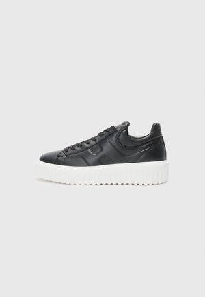 Zapatillas de cuero negro con una suela blanca gruesa, con puntera redonda, diseño con cordones, acentos laterales texturizados y acabado suave.