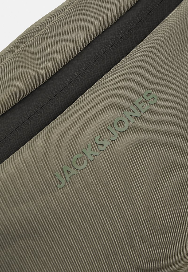 Bolsa de tela verde con una superficie texturizada, que presenta un cierre negro y el logo grabado "JACK & JONES". Forma rectangular, material duradero.