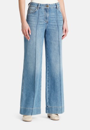 Jeans en denim bleu clair à jambes larges avec des coutures contrastées, présentant une taille mi-haute et une fermeture à bouton. Poches avant visibles.