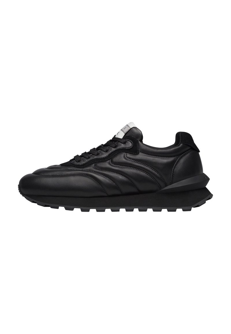 Sneaker in pelle nera con una texture liscia, forma arrotondata, suola spessa e chiusura con lacci. Presenta cuciture curve e un accento posteriore.