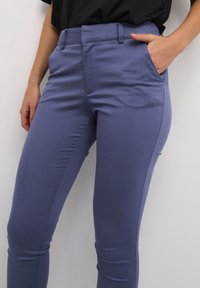 Valkoiset vaaleanpunaiset slim-fit-housut, jotka on valmistettu sileästä kankaasta. Housuissa on sivutaskut ja litteä etuosa. Muotoiltu tiiviin istuvuuden saavuttamiseksi.