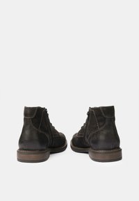 Botas de cuero negro hasta el tobillo con cierres de cremallera, punta redonda, acabado texturizado y detalle de costura en contraste en las suelas de goma.