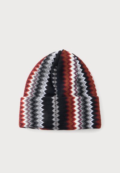 Bonnet tricoté avec motif en zigzag en noir, blanc, gris et couleurs rouille, revers plié, présenté sur un fond clair.