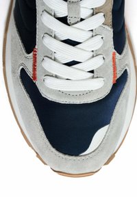 Sneaker blu navy e grigio con una tomaia in suede testurizzato, dettagli in tessuto liscio, lacci bianchi e suola in gomma marrone chiaro.