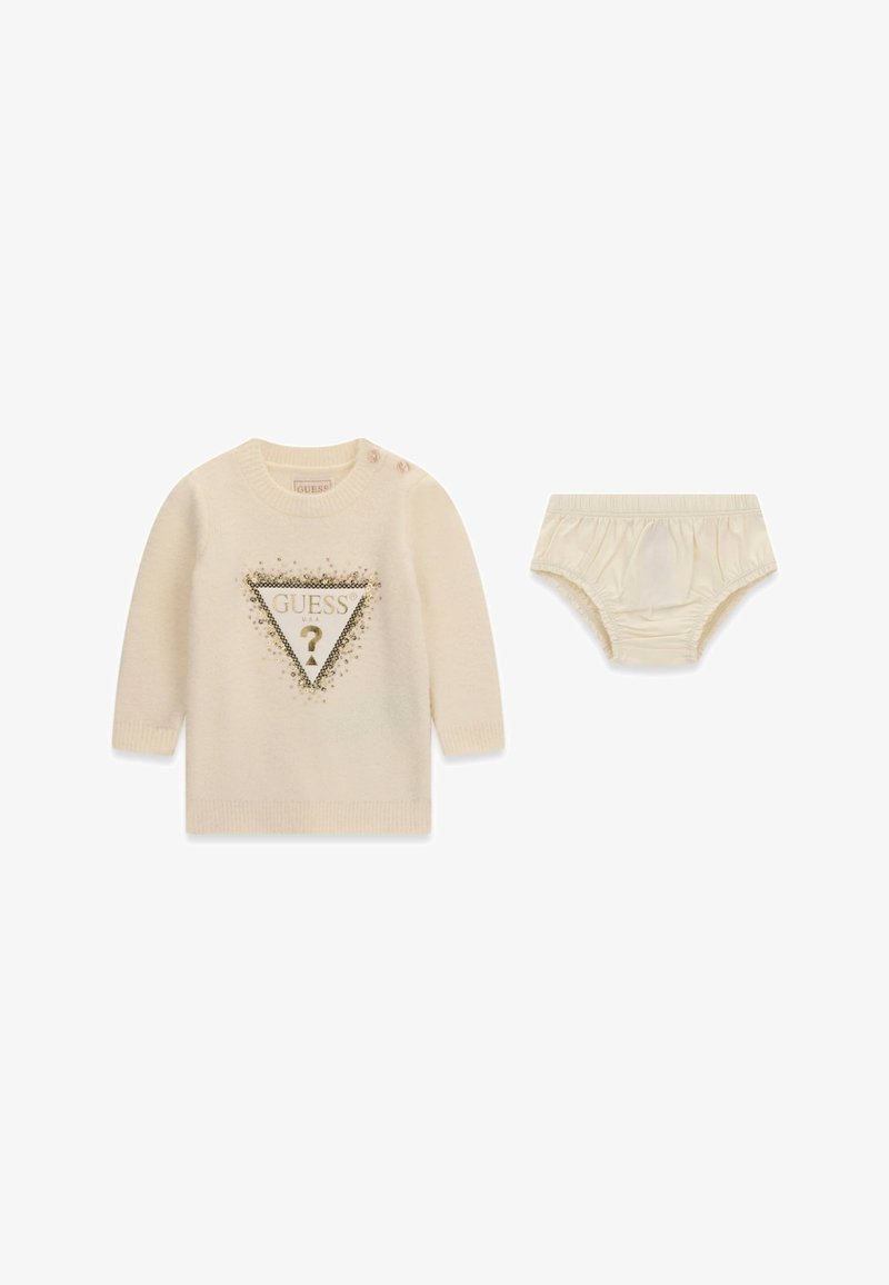 Pull bébé couleur crème avec logo doré "GUESS" et culotte de couche beige assortie avec taille élastique et ouvertures pour les jambes.
