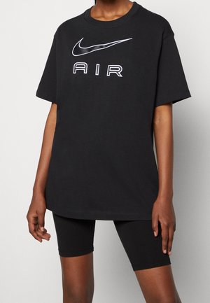 Black cotton oversized t-shirt with a white Nike logo and "AIR" text. Paired with black bike shorts, featuring a smooth, fitted texture.