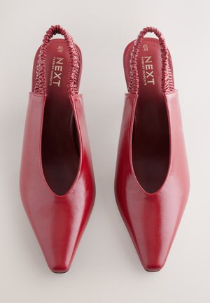 Red leather slingback shoes with a pointed toe, elasticated strap, and a glossy finish. Brand name "NEXT" visible on the insole.