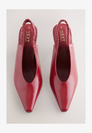 Røde læder slingback-sko med spids tå, elastisk rem og blank finish. Mærkenavnet "NEXT" synligt på indersålen.