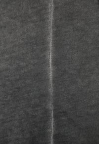 Tmavošedá tkanina s jemnou strukturou, vykazující jemný lesk. Obsahuje svislý šev uprostřed. Rovnoměrné rozložení barvy.