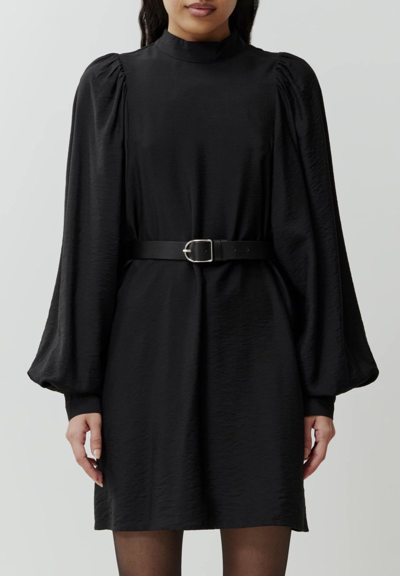 Zwarte jurk met pofmouwen en hoge halslijn, cinched in de taille met een zwarte riem, voorzien van een gladde textuur en een lengte tot de knie.